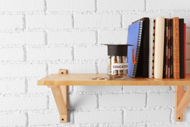 a wooden shelf with books and a cup on it.