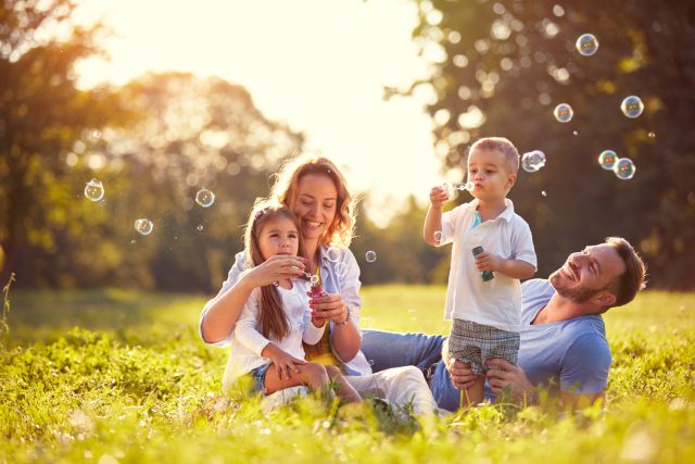 a family blowing bubbles in a field at sunset.